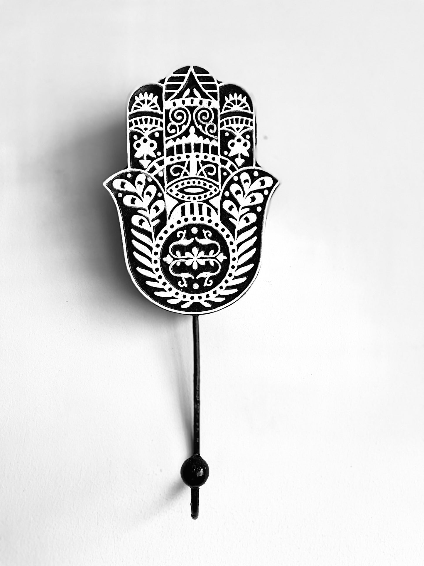 A very common motif of the Boho or Bohemian style is the The Hamsa Hand. It symbolizes the “Hand of God” and has been traditionally believed to provide defense against the evil eye.  We bring to you the beautifully hand carved wooden motif with cast iron hook.  You can use the same as wall- mounted key holder or can hand your other belongings on the same.  Material: Sheesham wood  Specialty: Hand carved by local artisans of the Thar Desert, India